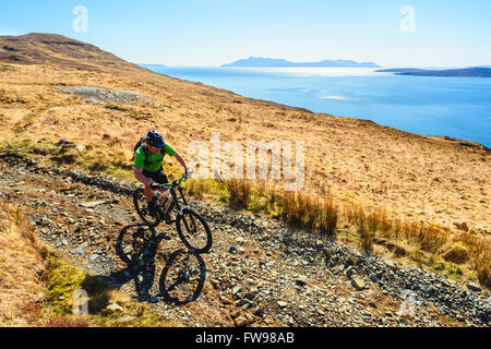 Mountainbiker absteigend nach Camasunary Isle Of Skye Schottland mit der Insel Rum am Horizont Stockfoto
