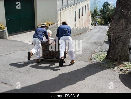 FUNCHAL, PORTUGAL-März 19 Rodelbahn Fahrer mit Schlitten mit Tauchen Touristen am 19. März 2016 in Monte Funchal, Portugal. Das ist Stockfoto