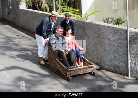 FUNCHAL, PORTUGAL-März 19 Rodelbahn Fahrer mit Schlitten mit Tauchen Touristen am 19. März 2016 in Monte Funchal, Portugal. Das ist Stockfoto