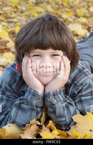 Kleiner Junge im Herbstlaub liegend Stockfoto