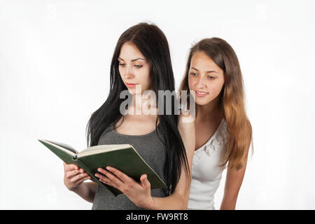 Schöne Mädchen gucken in Freundin das Buch, auf einem weißen Hintergrund Stockfoto