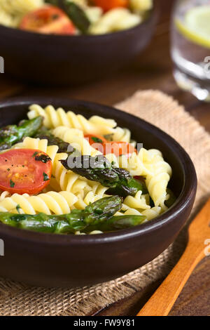 Gebackene grüner Spargel, Kirschtomaten und Rotini Nudelsalat in rustikalen Schüssel serviert Stockfoto