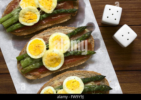 Grüner Spargel, Schinken, hart gekochtes Ei und geriebenem Käse warm Sandwich auf Backpapier gebacken Stockfoto