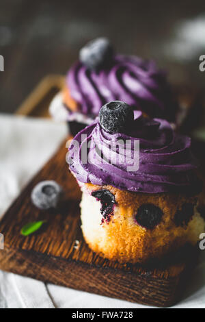 Blueberry Cupcakes mit lila Buttercreme auf Holzbrett, hautnah. Unaufdringlich, selektiven Fokus Stockfoto