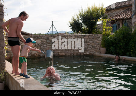 Vater und Sohn einen Eimer Wasser über Opas Kopf gießen Stockfoto