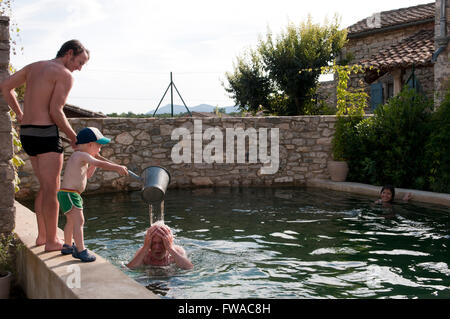 Vater und Sohn einen Eimer Wasser über Opas Kopf gießen Stockfoto