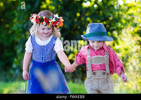 Kinder in bayerischer Tracht im Weizenfeld. Deutsche Kinder essen Brot und Brezel während Oktoberfest in München. Stockfoto