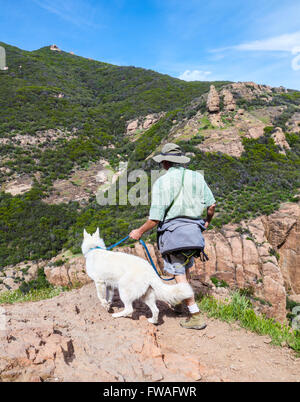 Wanderer und Hund auf dem MIshe Mokwa Trail im Kreis X Ranch, mit Echo Klippen, Felsen Bergsteiger und Balanced Rock im Hintergrund Stockfoto