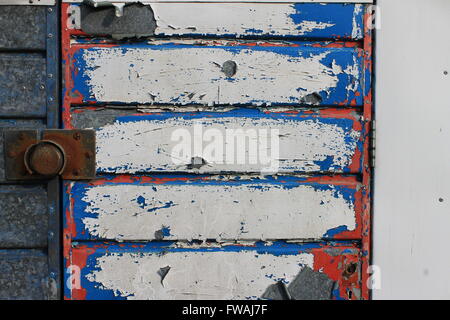 Abblätternde rot-weiß-blaue Farbe auf alten Metall Garagentor Stockfoto