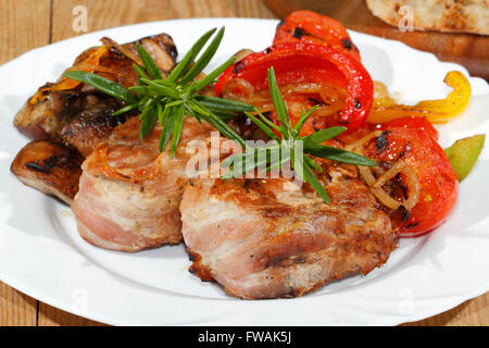 Gegrillte Schweinsmedaillons mit Champignons, Paprika, Tomaten auf einem Teller Stockfoto