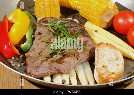 Gegrilltes Rindersteak mit Spargel, Paprika, Maiskolben in einer Pfanne Stockfoto