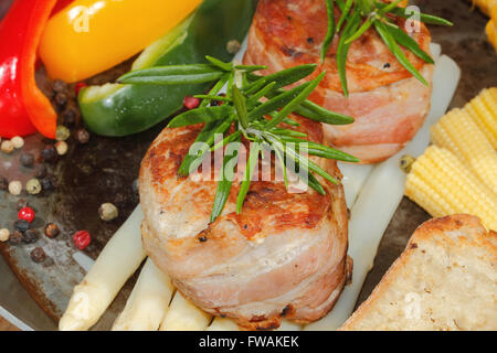 Gegrillte Schweinsmedaillons mit Spargel, Maiskolben, Paprika, Tomaten in einer Pfanne Stockfoto