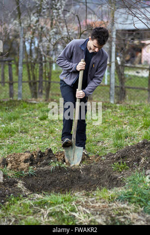 Teenager im Urlaub in den Boden graben, Bäume zu Pflanzen Stockfoto