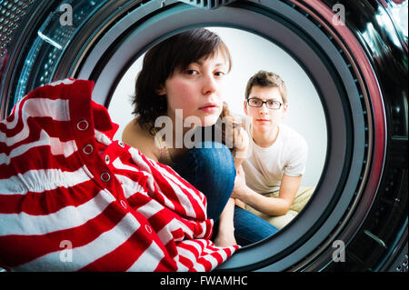 Lustige paar laden Kleidung, Waschmaschine Stockfoto