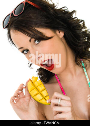 Gesunde junge Frau mit einem Stück Mango-Frucht vor einem weißen Hintergrund isoliert Stockfoto