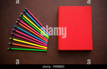 Hölzerne Schriftsteller Desktop mit bunten Bleistift und rote leere Cover Buch