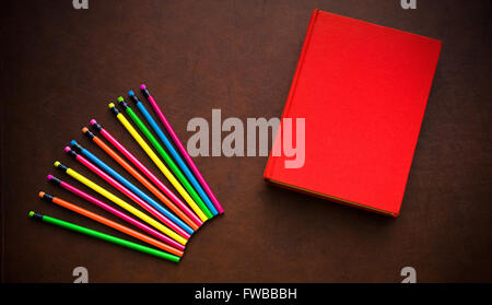 Hölzerne Schriftsteller Desktop mit bunten Bleistift und rote leere Cover Buch Stockfoto