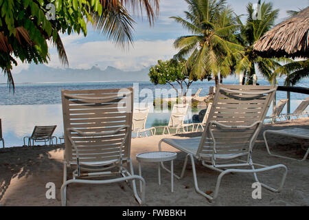 Tahiti, Französisch-Polynesien, Liegestühle am Strand in Papeete, Thaiti mit den Bergen von Moorea im Hintergrund. Stockfoto