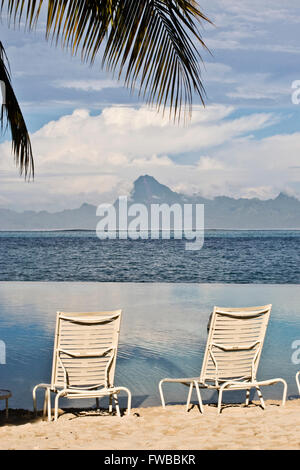 Tahiti, Französisch-Polynesien, Liegestühle am Strand in Papeete, Thaiti mit den Bergen von Moorea im Hintergrund. Stockfoto