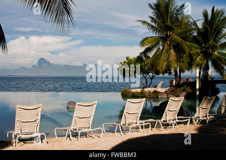 Tahiti, Französisch-Polynesien, Liegestühle am Strand in Papeete, Thaiti mit den Bergen von Moorea im Hintergrund. Stockfoto