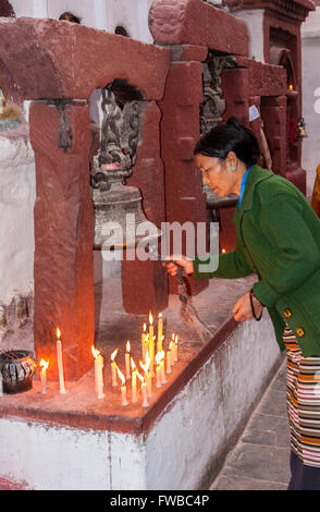 Bodhnath, Nepal.  Buddhistische Frau Läuten der Glocke vor dem Betreten eines Tempels. Stockfoto