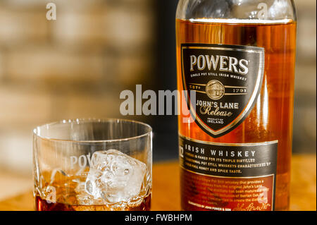 Eine Flasche Befugnisse einzigen Topf noch Irish Whiskey mit einem Glas Whiskey mit Eiswürfeln. Stockfoto