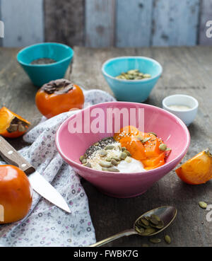 Frühstück Schüssel mit Joghurt, garniert mit Supernahrungsmittel Samen und Kaki Stockfoto