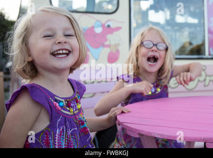 Zwei Kinder, die Spaß und Lachen in Lila Stockfoto