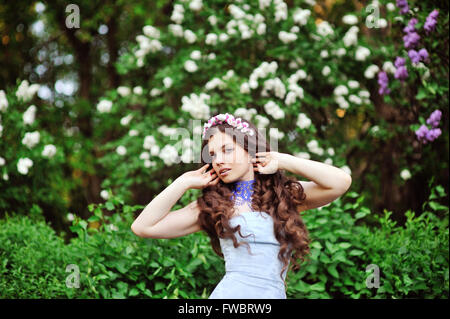 Porträt der jungen Frau in der Nähe der blühenden Flieder Stockfoto