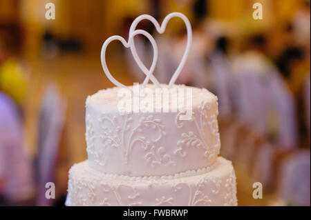 Multi-tiered weiße Hochzeitstorte mit oben zwei Herzen Stockfoto