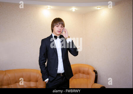 Bräutigam im schwarzen Anzug am Telefon sprechen Stockfoto