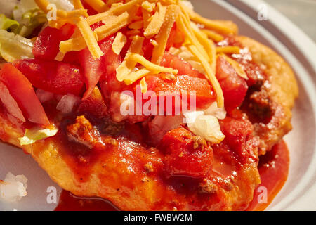 Moderne Indianer Kochen; ein Stück Frybread bedeckt mit Chili, Salat, Tomaten und Käse Fetzen, einem indischen Taco Stockfoto