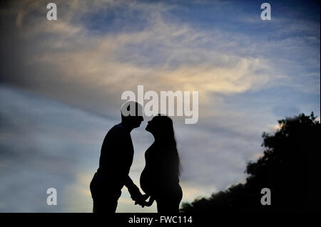 Ein junger Mann und seine schwangere Frau bei Sonnenuntergang. Silhouetten Stockfoto