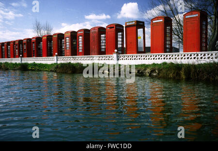 Sammlung von roten Telefonzellen aufgereiht und am Rande eines kleinen Sees, die die Farbe und Form im Wasser. Stockfoto