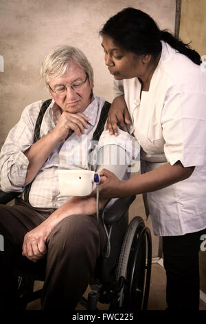 Krankenschwester, die Messung des Blutdrucks von einem älteren Mann im Rollstuhl Stockfoto