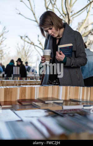 Eine junge Frau blättert Bücher auf einer im freien verwendeten Buchmarkt in London Stockfoto