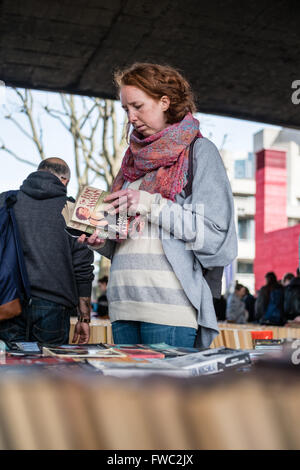 Eine junge Frau blättert Bücher auf einer im freien verwendeten Buchmarkt in London Stockfoto