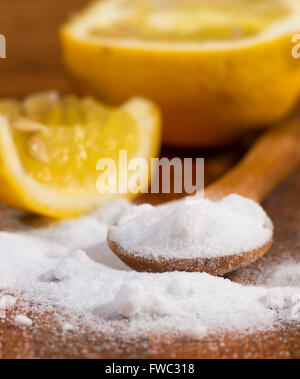 Backpulver (Natriumbicarbonat) in einem Holzlöffel und Zitrone Stockfoto