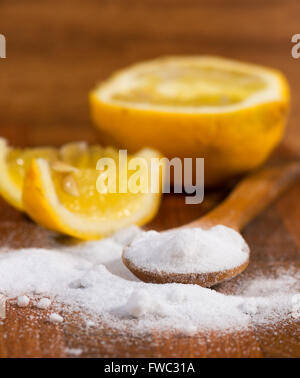 Backpulver (Natriumbicarbonat) in einem Holzlöffel und Zitrone Stockfoto