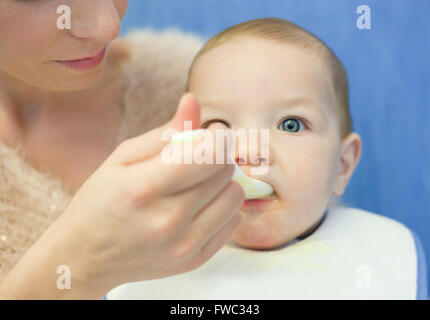 8 Monate Baby junge von seiner Mutter mit Löffel gefüttert. Selektiven Fokus Stockfoto