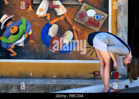 Eine Frau vor einer Wand keuchend in San Juan La Laguna, Sololá, Guatemala liegen. Traditionelle Maya-Malerei-Art Santiago A Stockfoto