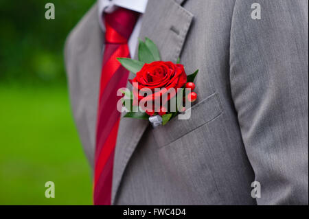 Red Rose Boutonniere auf grauen Anzug Stockfoto