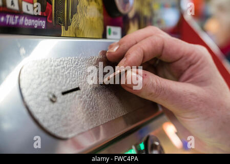 Eine Frau spielt eine 2P billiges Nudger Maschine in einer Kirmes in einem britischen Badeort. Stockfoto