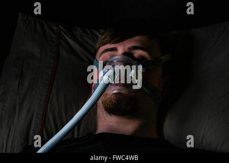 Ein Mann im Bett in der Nacht mit einem Philips Respironics System ein CPAP-Gerät mit Amara Ansicht Maske Stockfoto