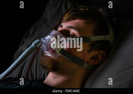 Ein Mann im Bett in der Nacht mit einem Philips Respironics System ein CPAP-Gerät mit Amara Ansicht Maske Stockfoto