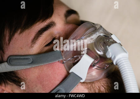 Ein Mann im Bett in der Nacht mit einem Philips Respironics System ein CPAP-Gerät mit Amara Ansicht Maske Stockfoto