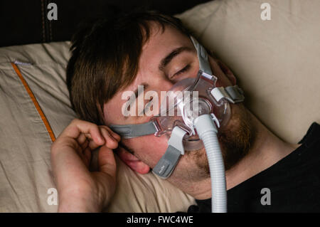 Ein Mann im Bett in der Nacht mit einem Philips Respironics System ein CPAP-Gerät mit Amara Ansicht Maske Stockfoto