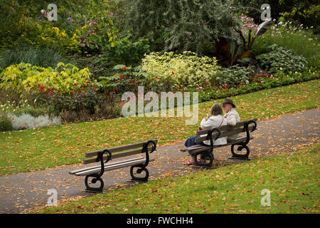 Valley Gardens, Harrogate, Yorkshire, England - älteres paar sitzen auf einer Bank, farbenfrohe Grenzen zu bewundern, im Chat & in diesem schönen Park entspannen. Stockfoto