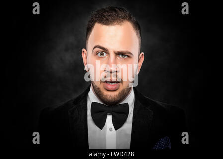 Schönen jungen Mann im schwarzen Anzug auf dunklem Hintergrund. Stockfoto