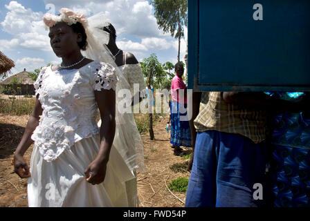 Lacekocot, Pader, Uganda. Freunde und Familie zu sammeln für die Gruppe Hochzeit von sechs Acholi Paare auf der Lacekocot-Flüchtlingslager. Eine Braut wartet geduldig vor der Kirche, umgeben von Gönnern Stockfoto